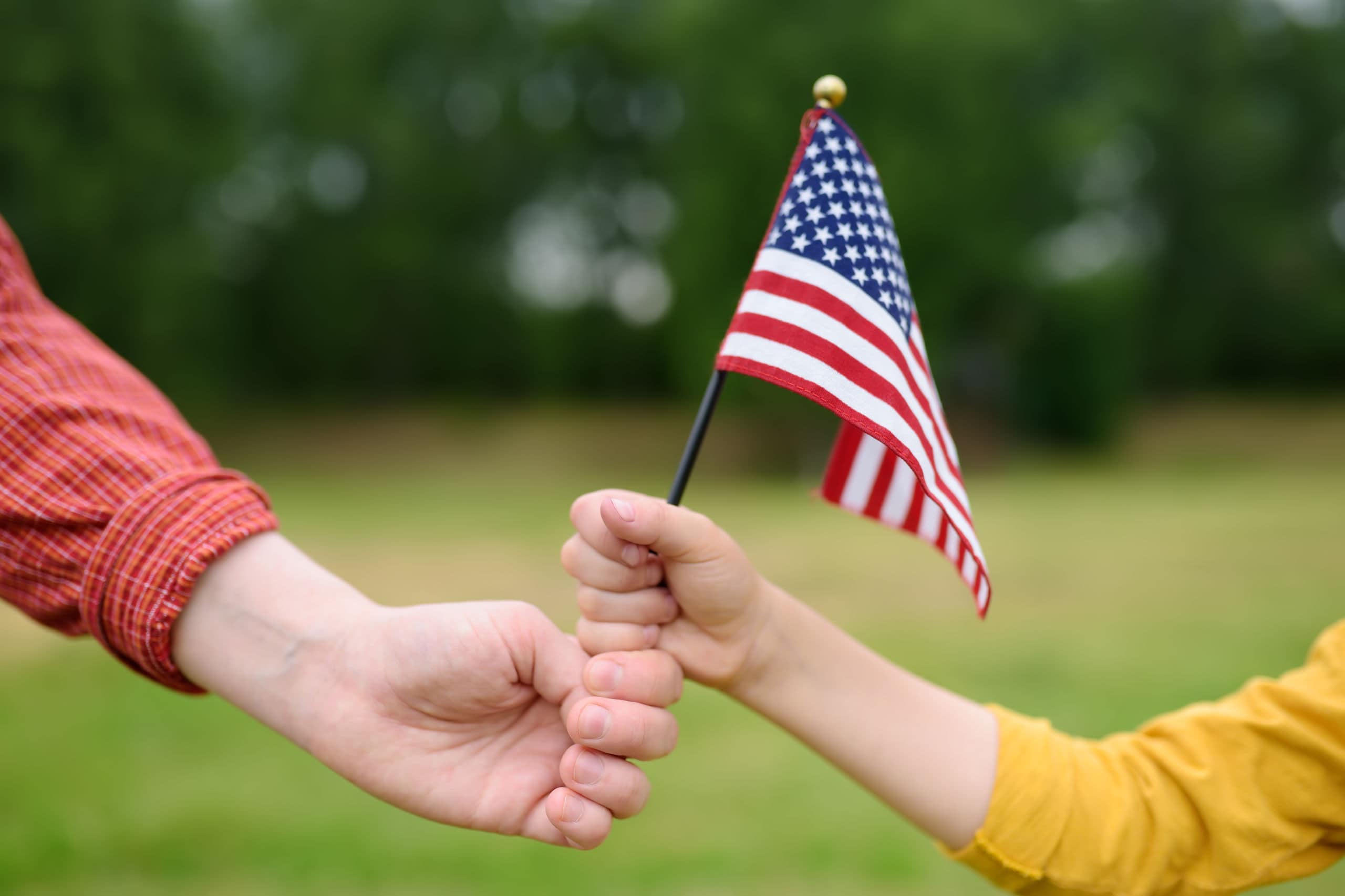 two hands holding a small american flag